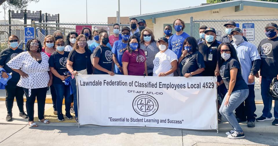 Classified employee members of the Lawndale Federation around a union banner