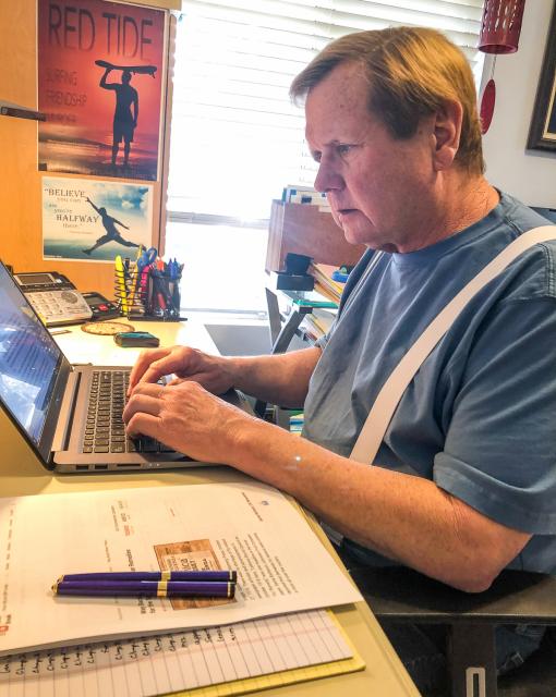 Mark James Miller sitting  at his laptop computer