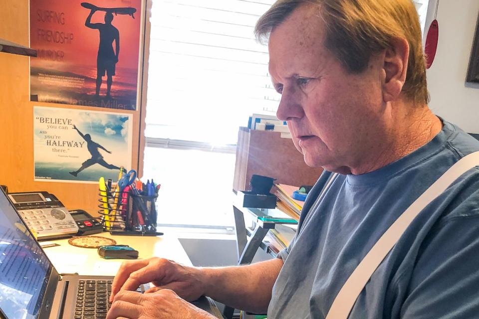 Mark James Miller sitting  at his laptop computer